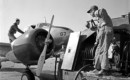 Ground crew using a fuel truck with a neoprene hose to refuel a Curtiss Wright AT 9A.